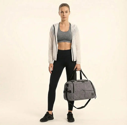 Woman holding a gray duffel bag against a beige background