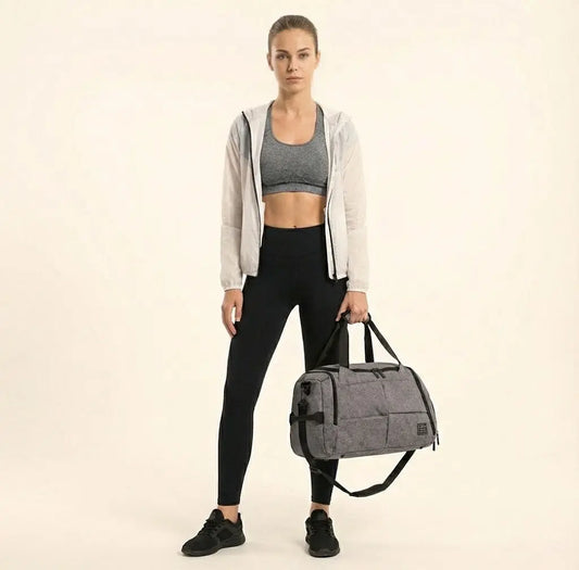 Woman holding a gray duffel bag against a beige background